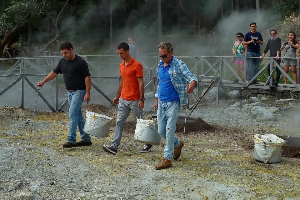 Köche heben Töpfe mit Cozido aus der heißen Erde in Furnas